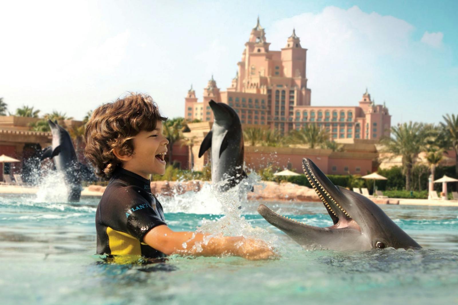 Veselé dítě plavoucí s delfíny v Aquaventure World