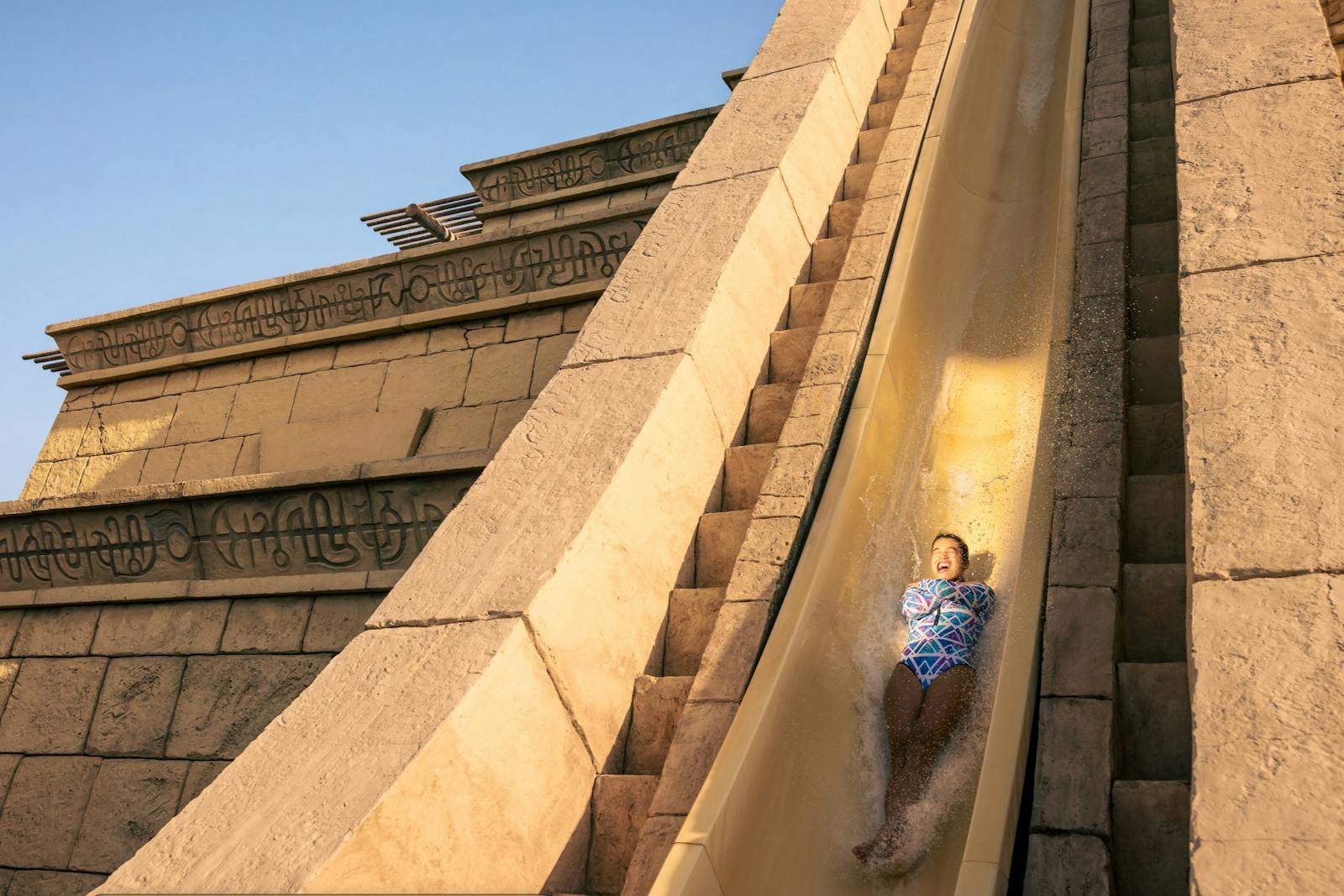 Meisje dat glijdt over een stenen structuur van Aquaventure World