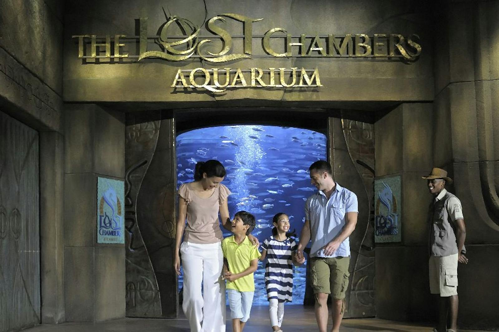 O familie vizitează Aquaventure World în fața unei ferestre mari